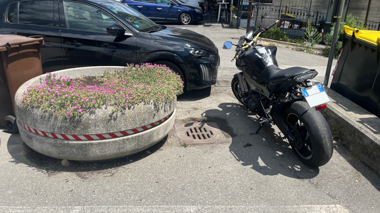 Il tombino protetto dalla fioriera, con una moto parcheggiata dietro
